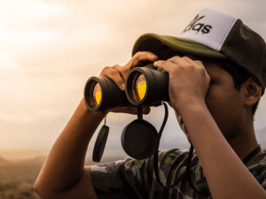Man looking though binoculars watching sunset