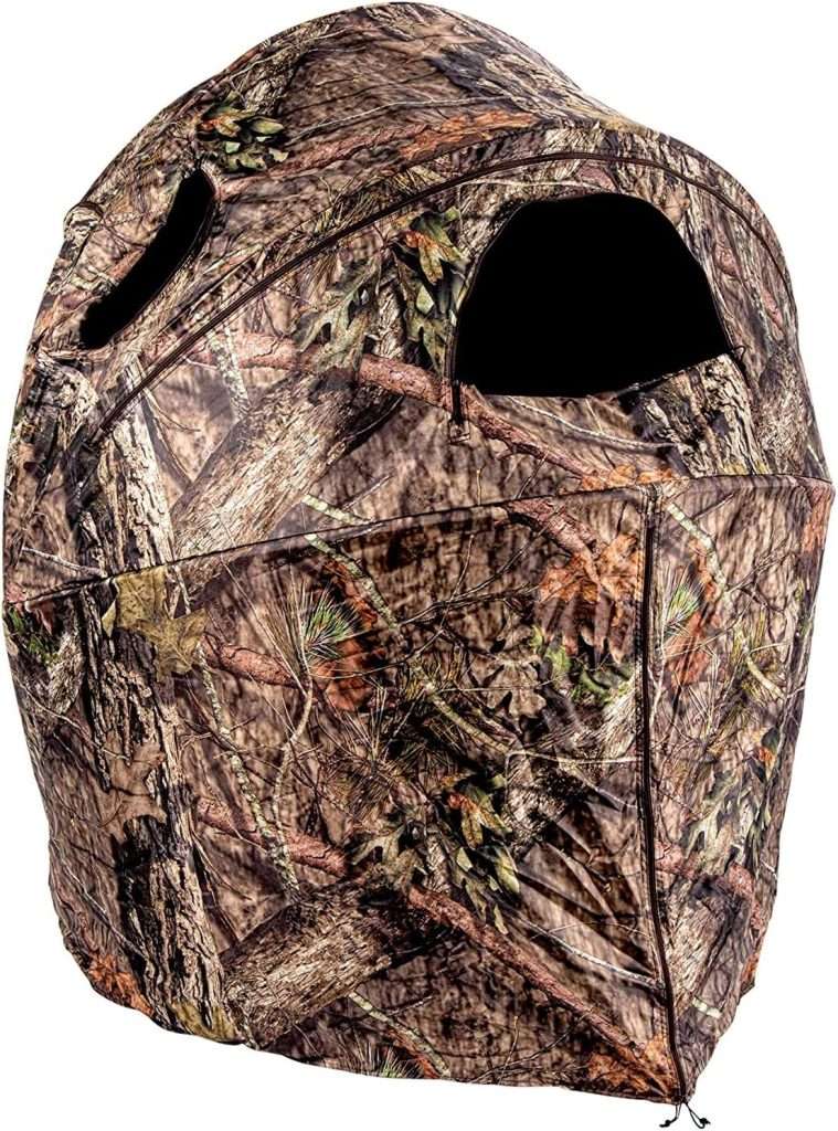 A camouflaged colored small tent with a lens sized hole in it.