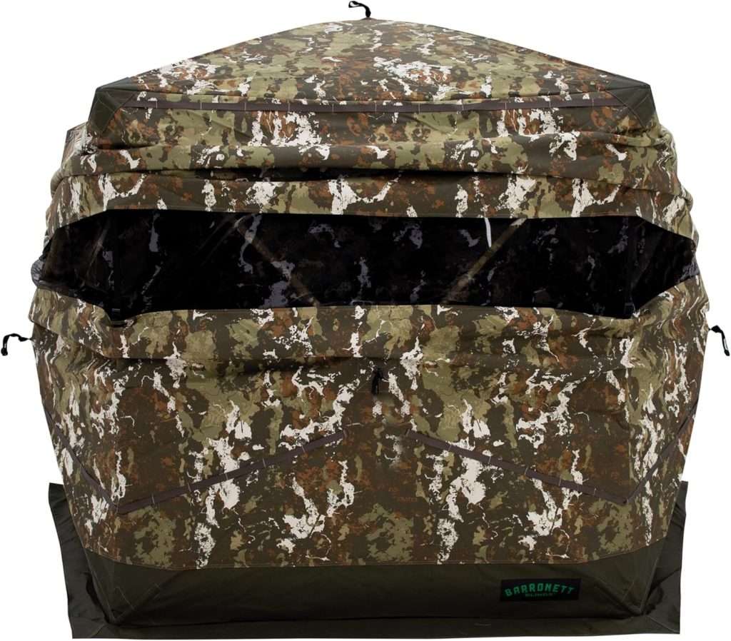 A camouflaged colored square tent with a lens sized hole in it.