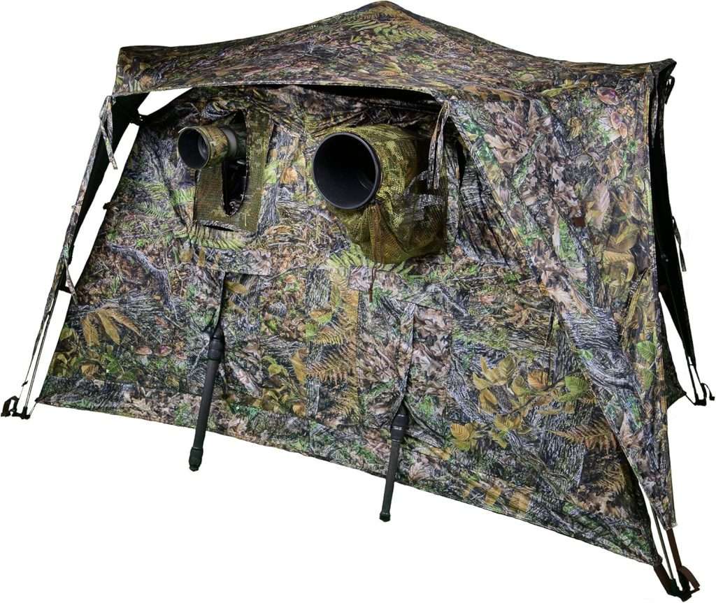 A camouflaged colored medium tent with a lens sized hole in it.