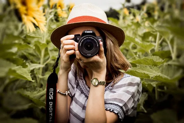 A head on shot of a woman holding up a camera.