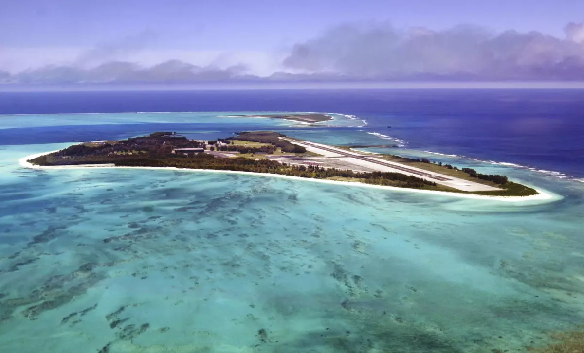An aerial shot of a sandy island in the middle of a turquoise ocean.
